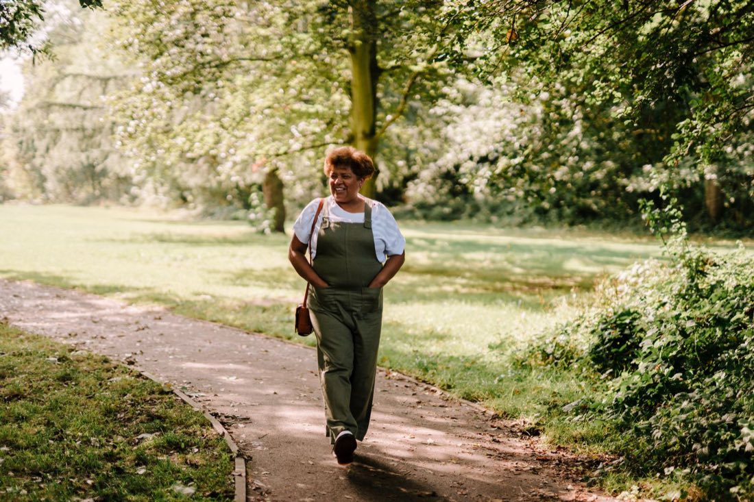A woman walking and laughing in a sunlit park